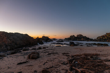 Wall Mural - Dawn view of rocky beach with clear sky.