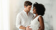 © Kevin - Happy loving mixed-race couple expecting a baby. Caucasian husband hugging his smiling beautiful pregnant African American wife. Maternity concept. Parenthood, future family.