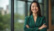 © Pete - Confident businesswoman in green suit smiles. Asian female executive in office. Successful career, leadership. Attractive woman poses, crossed arms. Modern portraiture, urban background.