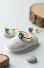 Poster - Elegant gold ring, earrings with blue topaz gems on white. Minimalist composition with stones, wood elements. Luxury product shot for jewelry brand, special occasion, engagement or fashion concept.