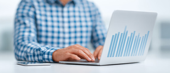 Poster - Person in checkered shirt types on laptop displaying bar graph, with smartphone nearby