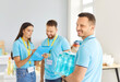© Studio Romantic - Smiling cheerful man carrying water bottles with his colleagues standing nearby with clipboard. Volunteers at humanitarian aid center preparing free food for donation to people in need. Food bank.