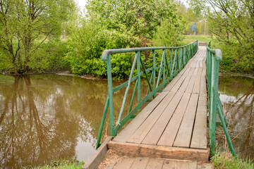 Poster - Wooden Bridge Over Calm Water Surrounded by Lush Greenery in a Quiet Nature Setting