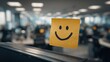 © Oleg - Bright yellow sticky note with smiley face in busy office environment during work hours