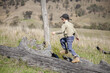 © Austockphoto - Young boy walking on a fallen log in a paddock