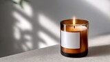 Candle is lit in a glass container, creating a warm and inviting atmosphere. The candle is positioned on a table, and its light casts a soft glow on the surrounding area