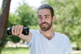 a young man is lifting dumbbells outdoors