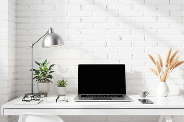 Poster - Laptop on white desk against brick wall in minimal workspace.