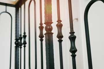 Poster - Elegant Black Iron Railings with Intricate Designs and Soft Sunlight Glimmering on Vintage Architectural Details