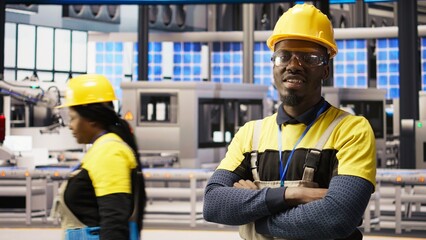Poster - Portrait of technician overseeing solar panel production lines equipment. African American man maintaining photovoltaic assembly systems in automated industry 4.0 factory using computer, camera A