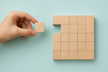 Poster - Strategic planning in progress as a carefully positions the final wooden block completing the organized grid structure symbolizing project development and precision