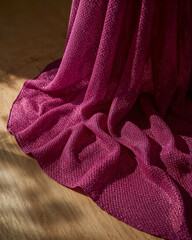 Poster - Exquisite Woven Fabric in Radiant Magenta, Draped Artfully on a Smooth Wooden Surface, Evoking Luxury and Sophistication