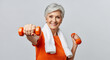 © Николай Срибяник - Smiling senior woman with gray hair exercising with orange dumbbells and a towel. Represents active aging, fitness, and a healthy lifestyle.