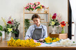 © Katcha - Female florist in apron writing details of order in notebook on the table while creating and making flower