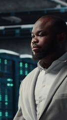 Poster - Vertical video Smiling engineer in server hub monitoring data center energy consumption across components. Happy IT expert walking in data center, making sure rigs sensors are functioning optimally