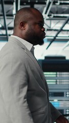 Poster - Vertical video System administrator walking in data center with rigs handling queries, doing backups. Admin overseeing server farm with gear hosting digital services, powering client platforms, camera