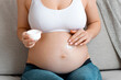 © Prostock-studio - Skincare During Pregnancy. Beautiful Pregnant Woman Applying Moisturising Cream On Her Naked Belly While Sitting On Couch In Living Room, Making Anti Stretch Marks Treatment For Skin On Tummy