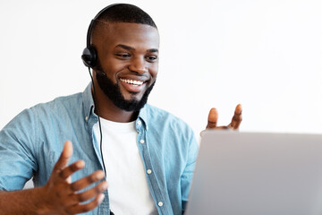 Poster - Video Conference. Cheerful african american man in headset making web call on laptop at workplace in home office, enjoying online communication, positive black guy talking and gesturing at camera