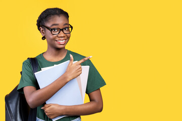Aufkleber - Smiling Black Female Student Pointing Finger Aside At Empty Space For Text Posing With Books And Notebooks Standing Over Yellow Studio Background. Great Educational Offer Advertisement