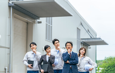Poster - 工場の前で悩む従業員グループ