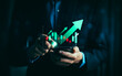 © Sutthiphong - Businessman analyzing bullish stock market trend on smartphone with rising candlestick chart and green arrow growth indicators, concept of trading, investment success, financial analytics, and profit