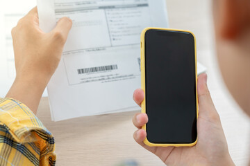 woman use phone scan barcode or qr codes to pay credit card bill after receiving document invoice. p
