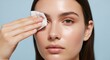 © NeuroCake - Woman degreasing skin with a special cleansing wipe on beige background. Skincare cleansing routine. Beauty and skin preparation concept. Image for banner, poster. Portrait with copy space.
