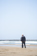 © Masakazu Tokashiki - By the rippling Sea of Japan on a sunny May day, a Japanese man in his late 70s wearing a checkered shirt stands alone on the beach. Gentle waves and spring air evoke a quiet moment of reflection.