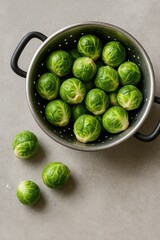 Poster - Fresh Brussels sprouts in metal colander on gray kitchen counter, healthy cooking ingredient flatlay
