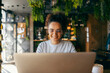 © Dusan Petkovic - Portrait of happy interracial girl using her laptop and smiling at it at coffee shop.