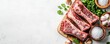 © JS - Farm to table Fresh raw meat cuts arranged on a rustic surface with herbs and spices, emphasizing culinary preparation.