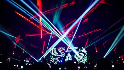 Poster - Colorful laser lights illuminating a night concert create an electrifying atmosphere as enthusiastic fans capture videos and photos on their smartphones, celebrating the vibrant performance