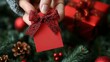 © jiknoo - Hand holding a red gift tag with a ribbon, near a festive setting