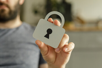 Poster - Close-up of a person holding a paper cutout of a padlock, symbolizing data protection and online security.