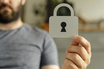 Aufkleber - Stock photo of a man holding a paper cutout of a padlock, symbolizing security and data protection.
