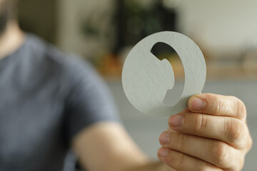 Poster - Close-up of a person holding a paper cutout of a phone icon, representing communication or contact.