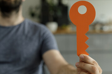 Poster - Stock photo of a man holding a large orange paper key.  Represents access, opportunity, or solutions.