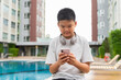© Ranta Images - Teenage Boy at Poolside During Summer Using Phone