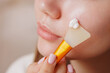 © st.kolesnikov - Closeup of woman using spatula to apply moisturizing face cream, skincare, hydration, beauty, soft skin, facial routine, selfcare, healthy glow.