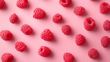 A flat lay composition showcases delicious ripe raspberries scattered beautifully on a pink background.

