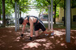 © GREGORIO - Young athlete doing calisthenics kneeling on the ground in a park