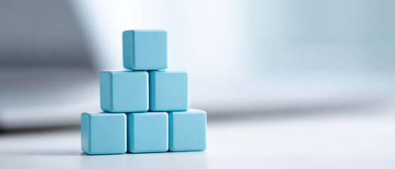 Poster - Blue cubes stacked in pyramid shape on white surface, with blurred background