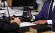© Wasan - Lawyers discussing legal fees using calculator in law office. Two lawyers are discussing legal fees for a new contract using a calculator, highlighting the financial aspects of legal representation.