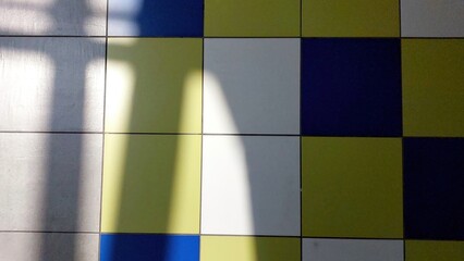 Poster - Colorful Tiled Floor With Shadow Patterns Creating Visual Contrast in a Well-Lit Space
