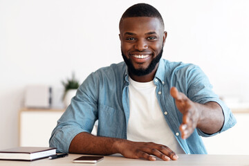Poster - Smiling Black Businessman Giving Hand For Handshake At Camera, Offering Partnership And Cooperation, Friendly African HR Manager Sitting At Desk In Modern Office And Greeting Somebody, Copy Space