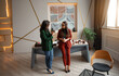 © My Ocean studio - Two stylish businesswomen chatting over coffee in a modern office. The bright workspace features elegant decor, large windows, abstract wall art, and a professional atmosphere.
