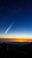 Wall Mural - Glowing comet streaks across the night sky over rolling dark mountain range with sunset colors and illuminated city lights far in the distance.