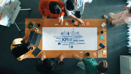 Poster - A vibrant team engages in a collaborative meeting centered around KPI objectives and strategic goals. The modern workspace highlights their focus on performance and alignment. Amity
