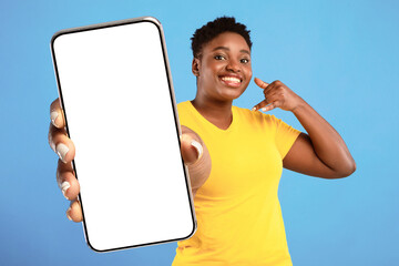 Poster - Call Me. Positive Plus Size African Woman Holding Hand Near Ear Like Phone And Pointing Finger At Camera Recommending To Contact Her Standing Over Blue Background. Studio Shot