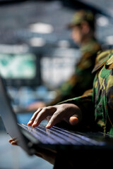 Poster - Close up of military server room worker typing on laptop, overseeing firewall configurations. Army information technology specialist in data center deploying software updates in secure facility